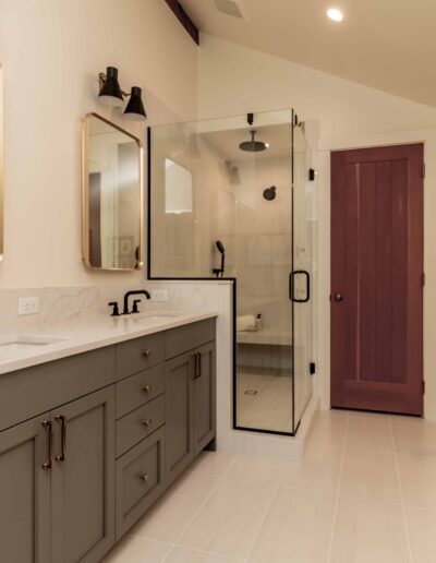 Modern bathroom with double sink vanity, glass shower, freestanding bathtub, and a wooden door; neutral color palette with black fixtures and accents.